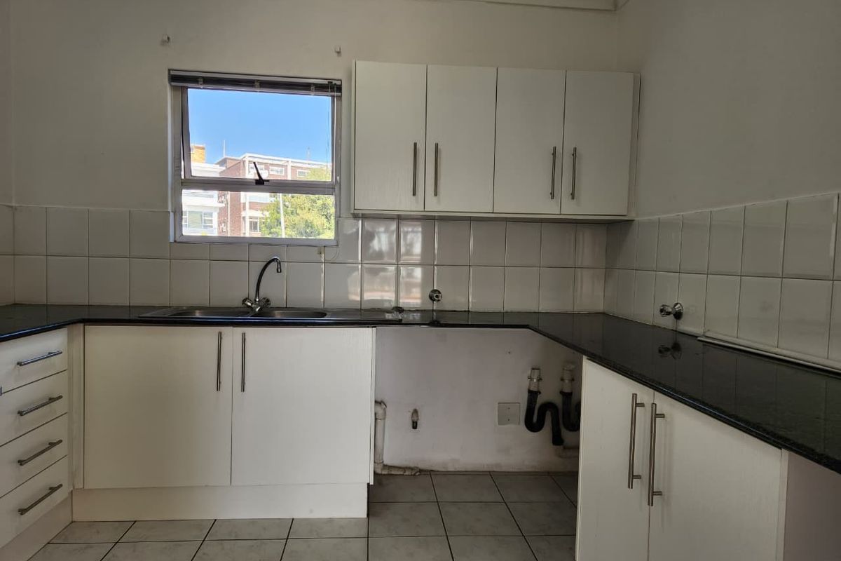 A functional kitchen featuring white cabinetry, dark granite countertops, tiled backsplash, and tiled flooring, with space prepared for appliance installation.