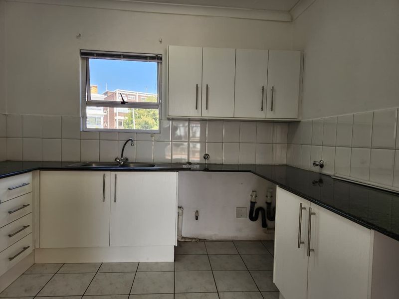 A functional kitchen featuring white cabinetry, dark granite countertops, tiled backsplash, and tiled flooring, with space prepared for appliance installation.
