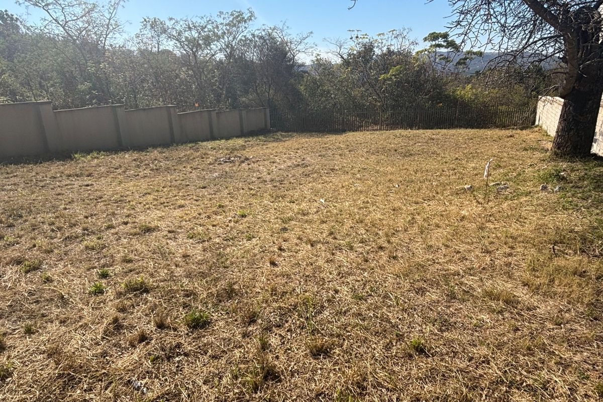 A vacant residential plot featuring a level grassed area enclosed by perimeter walls and fencing, offering a blank canvas for development.