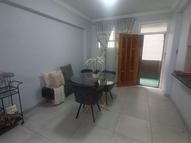 Open plan living and dining area featuring tiled flooring, granite kitchen countertops, and direct access to an outdoor balcony space.