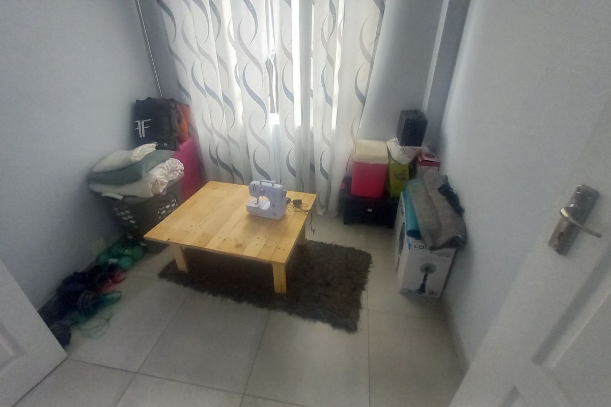A small, neutral-toned room featuring tiled flooring and window treatments, currently used as a utility or storage space.