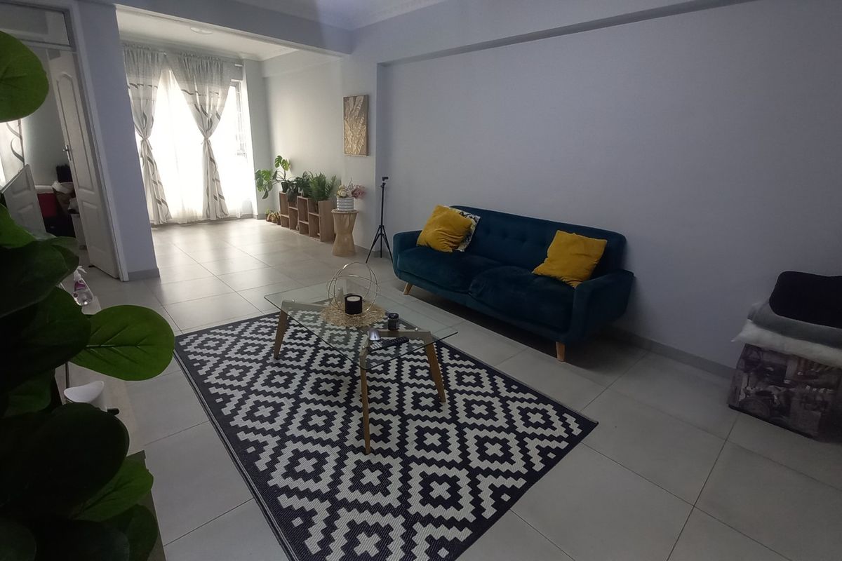 A bright and spacious living room featuring neutral tiled flooring and classic coved ceiling cornices, offering a clean and versatile living space.