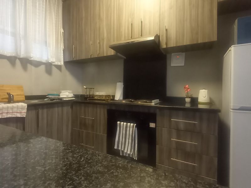 A functional kitchen featuring wood-grain cabinetry, dark granite countertops, a built-in oven, and an extractor fan.