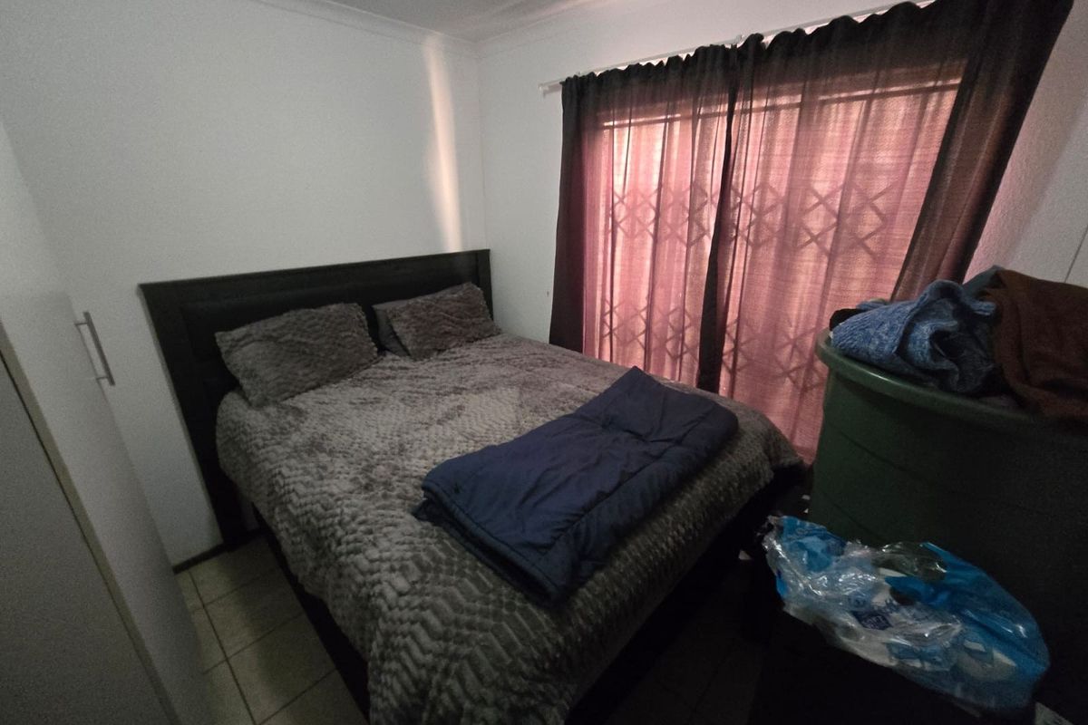 A functional bedroom featuring tiled flooring, a built-in cupboard, and a security gate over the window.