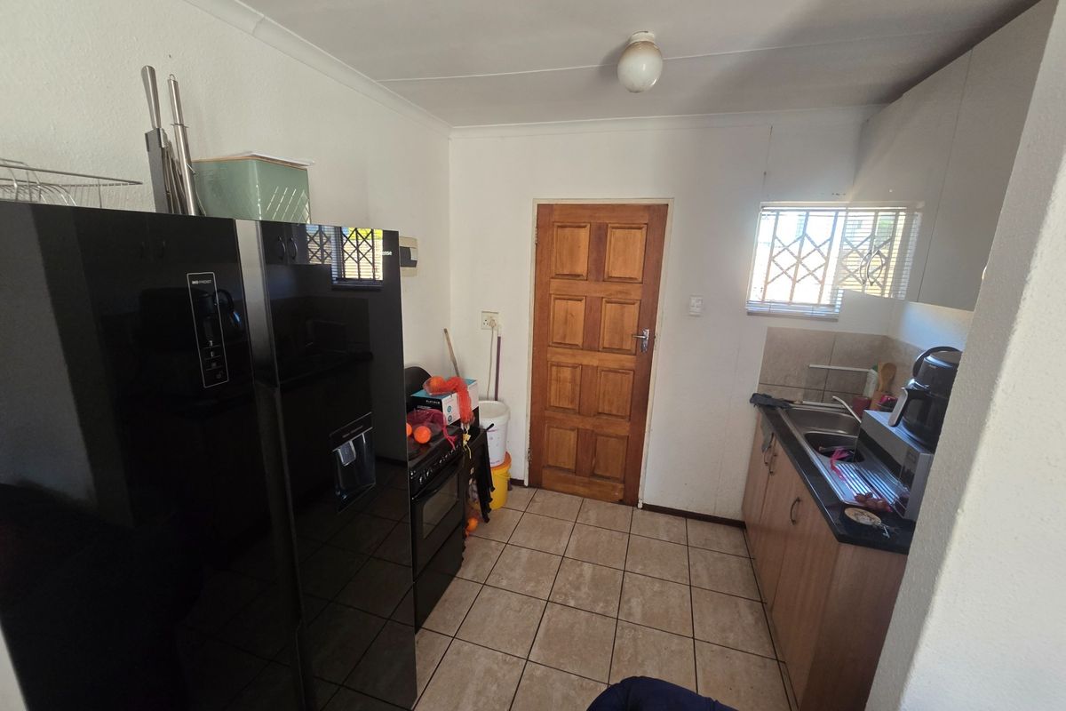 A compact kitchen featuring tiled flooring, built-in cabinetry, and a stainless steel sink, offering a functional layout with potential for modernization.