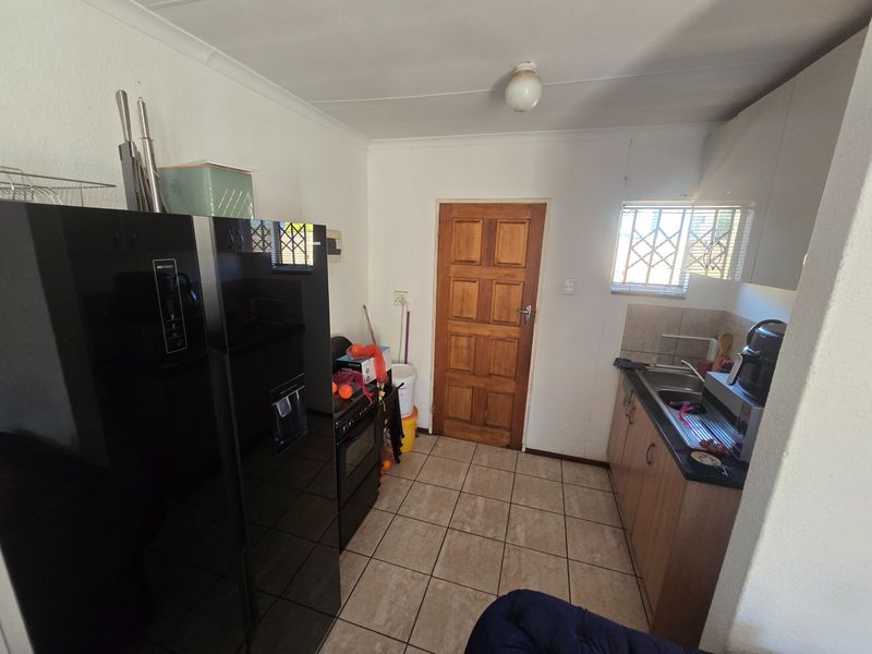 A compact kitchen featuring tiled flooring, built-in cabinetry, and a stainless steel sink, offering a functional layout with potential for modernization.