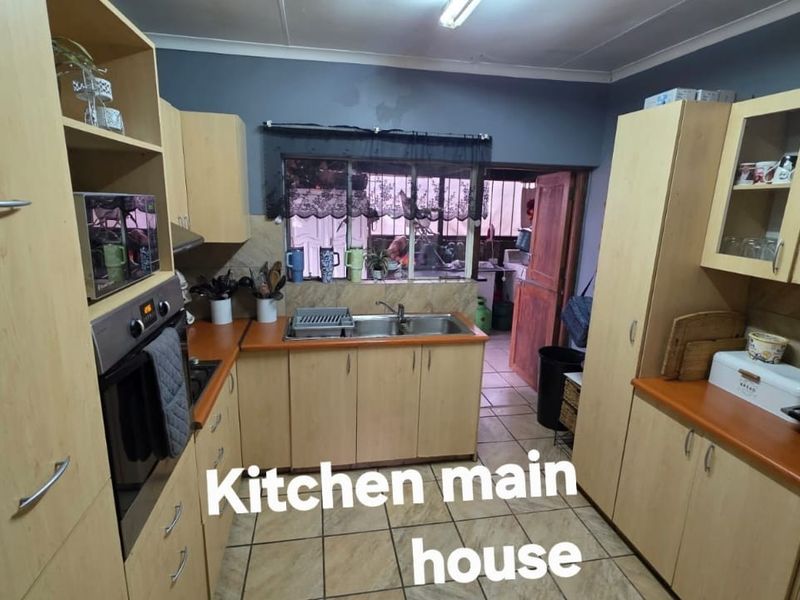 Functional kitchen featuring light wood cabinetry, laminate countertops, a stainless steel double sink, and built-in oven with tiled flooring.