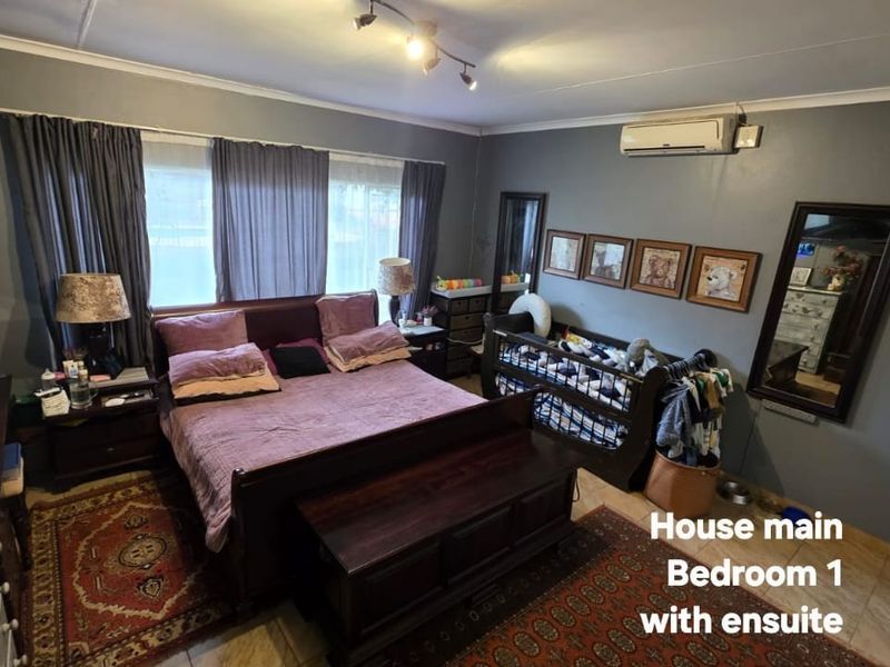 Spacious main bedroom featuring tiled flooring, a wall-mounted split-system air conditioner, and ceiling-mounted track lighting.