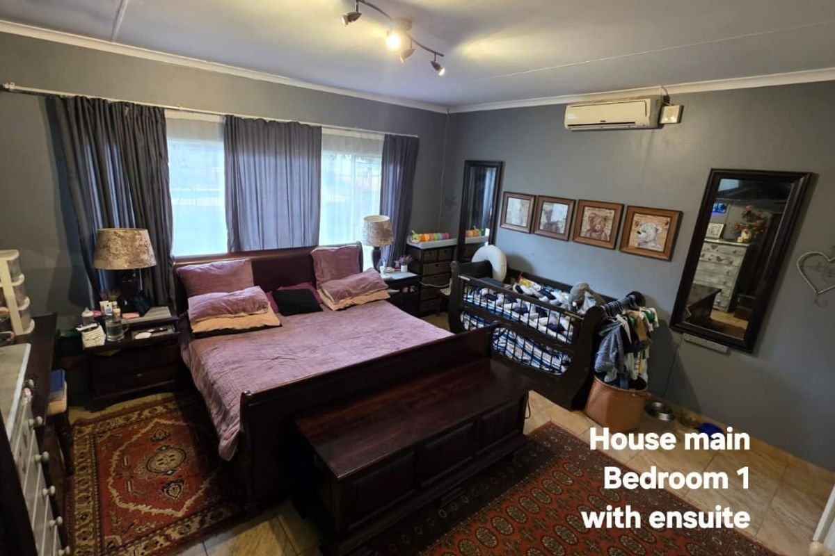 Spacious main bedroom featuring tiled flooring, a wall-mounted split-system air conditioner, and ceiling-mounted track lighting.