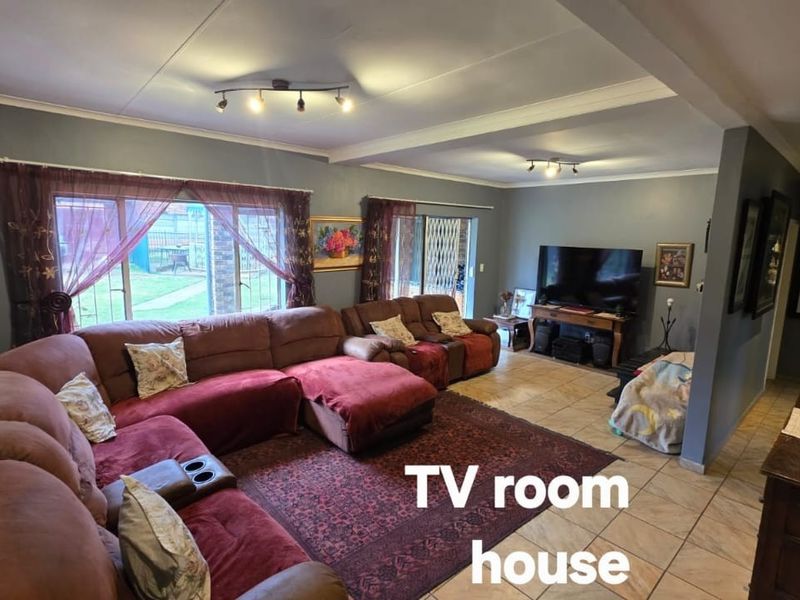 Spacious living room featuring tiled flooring, large sliding glass doors providing garden access, and modern recessed ceiling lighting.