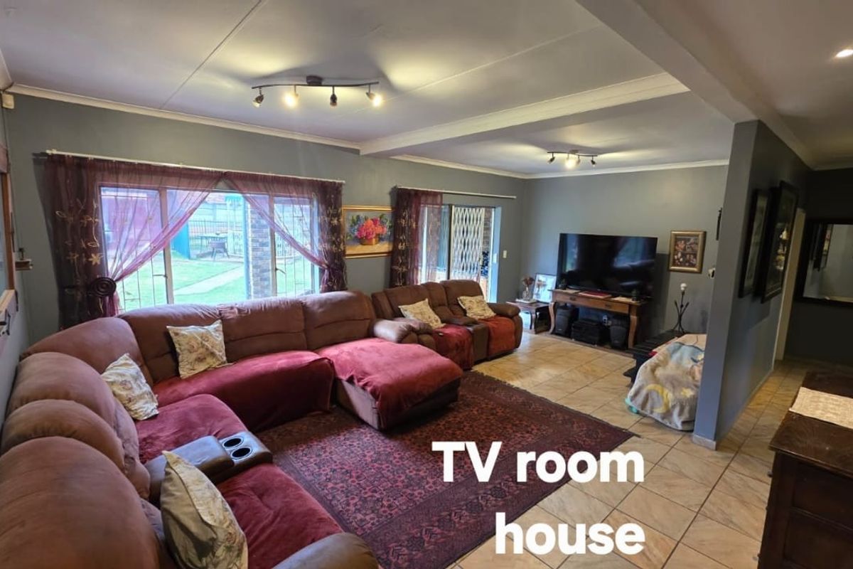 Spacious living room featuring tiled flooring, large sliding glass doors providing garden access, and modern recessed ceiling lighting.