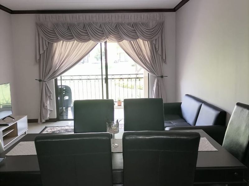 Open plan living and dining area featuring tiled floors, crown molding, and a sliding glass door leading to a balcony.