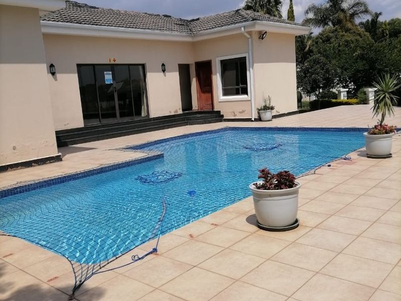 Outdoor pool area featuring a tiled deck, swimming pool with safety net, and direct access to the home via sliding glass doors.