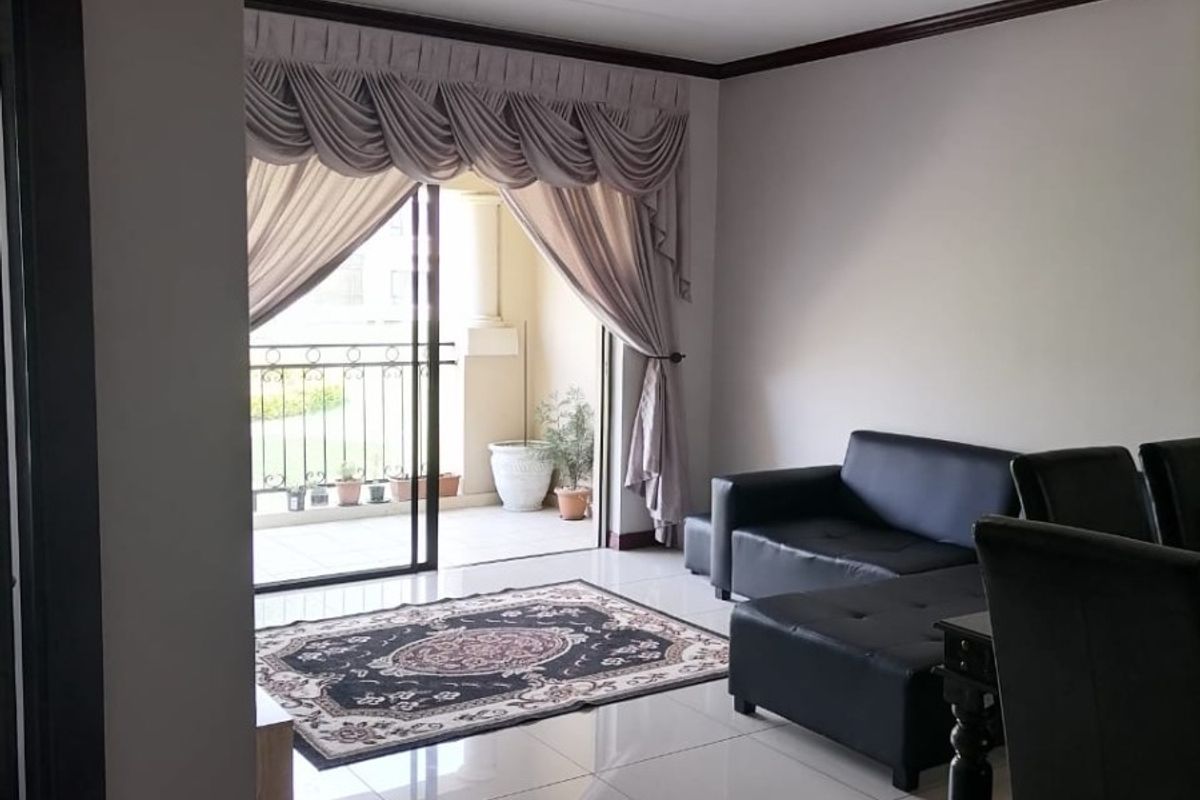 A bright living room featuring tiled flooring and a sliding glass door providing direct access to a private balcony.