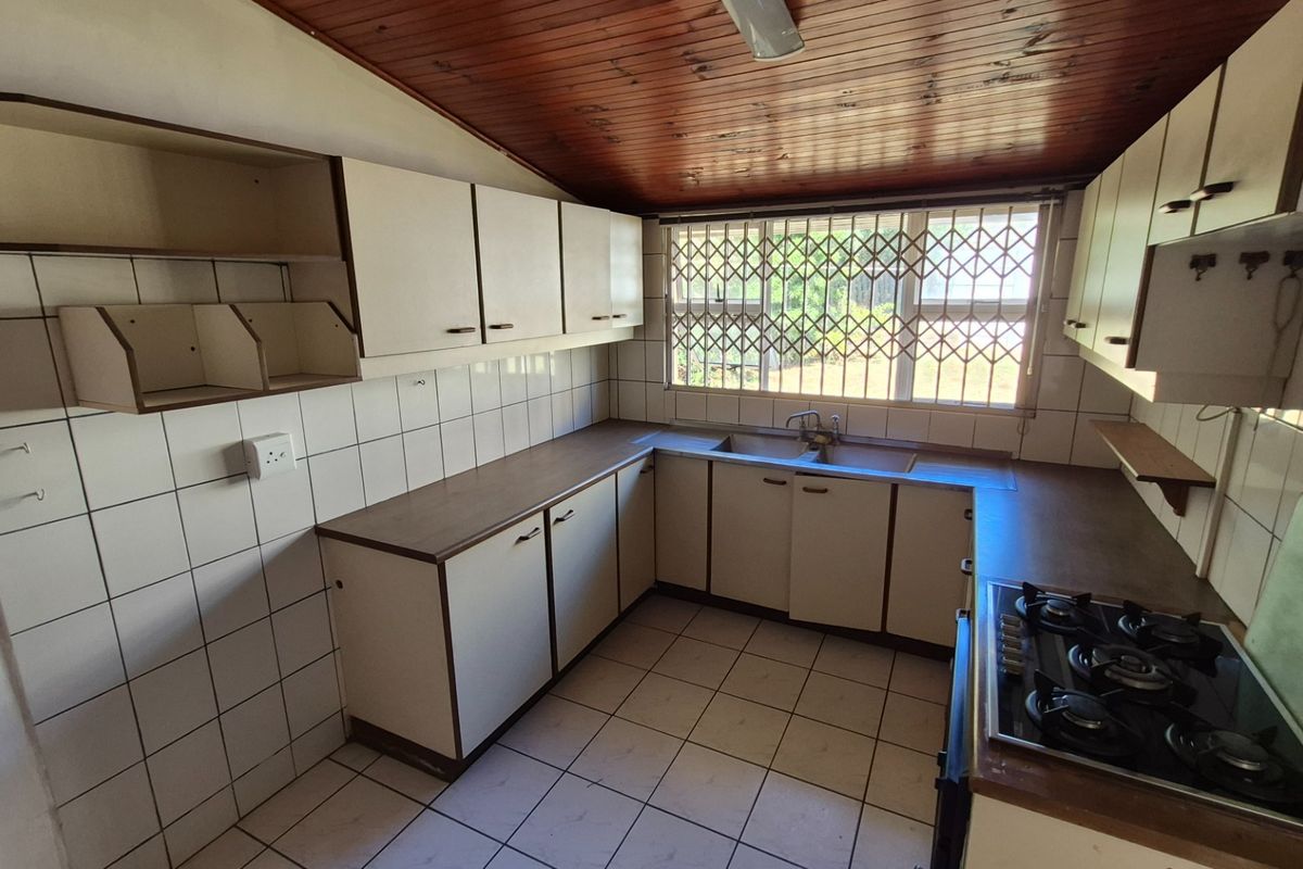 A dated kitchen featuring built-in cabinetry, laminate countertops, a gas hob, and tiled finishes, offering a functional layout ready for modernization.