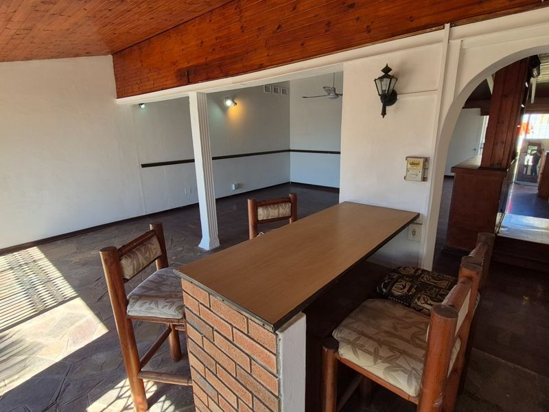 Open plan living area featuring a brick breakfast bar, timber-clad ceiling, and stone flooring, connected by a classic archway.