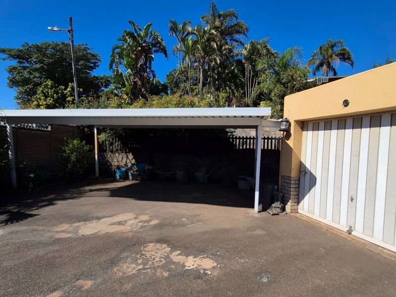 A functional outdoor area featuring a covered carport and an attached garage with a paved driveway.