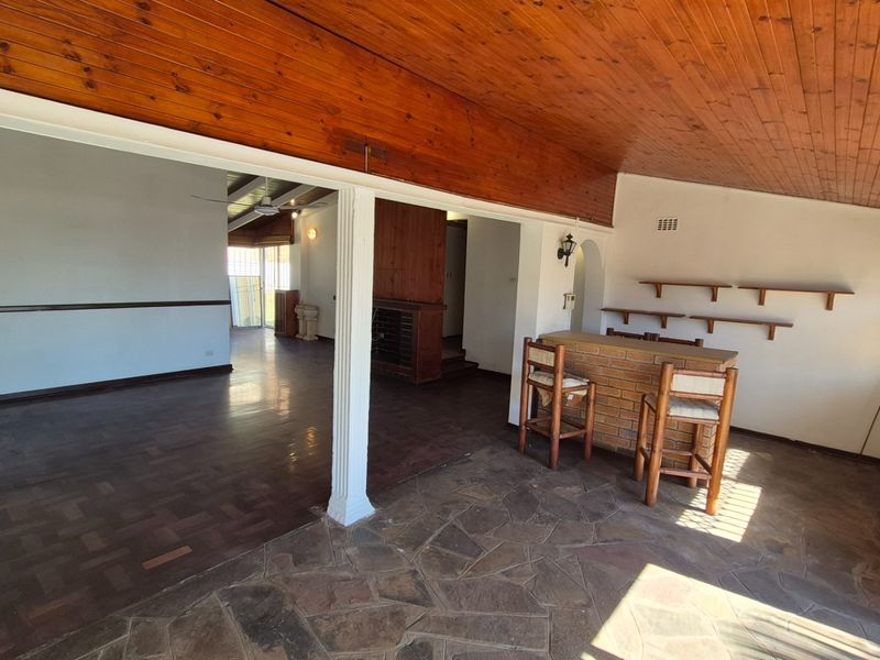 Open plan living area featuring a built-in brick bar, timber ceiling, and a combination of stone and parquet flooring.
