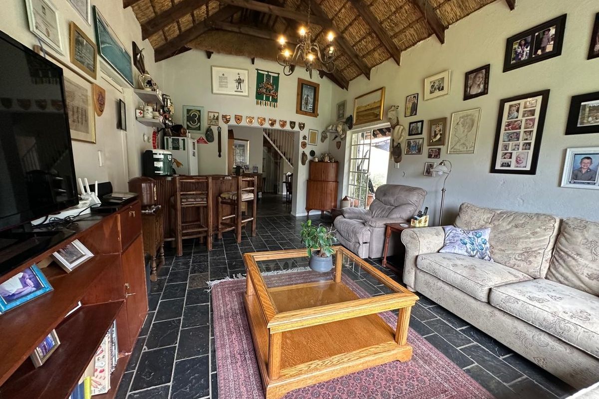Spacious living area featuring a high vaulted thatched ceiling with exposed timber trusses, slate flooring, and a built-in bar area.