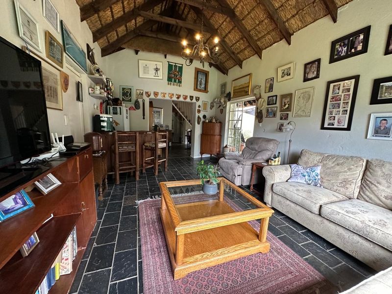 Spacious living area featuring a high vaulted thatched ceiling with exposed timber trusses, slate flooring, and a built-in bar area.