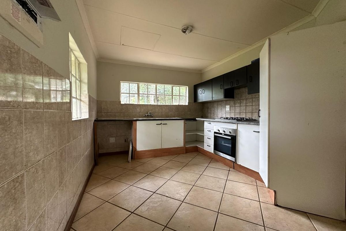 A functional kitchen featuring tiled flooring, built-in cabinetry, a gas hob, and an oven, offering a blank canvas for potential renovation and modernization.
