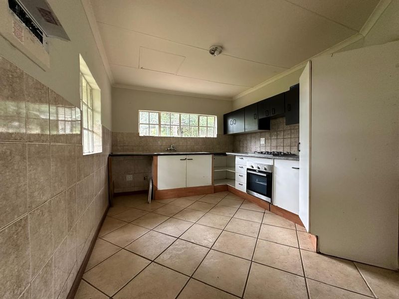 A functional kitchen featuring tiled flooring, built-in cabinetry, a gas hob, and an oven, offering a blank canvas for potential renovation and modernization.