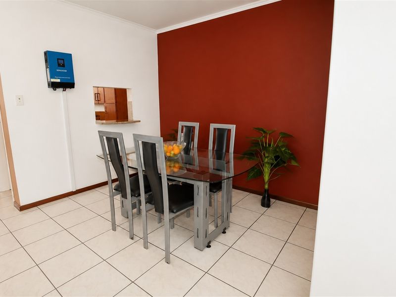 Dining area featuring tiled flooring, a wall-mounted inverter system, and a convenient serving hatch connecting to the kitchen.