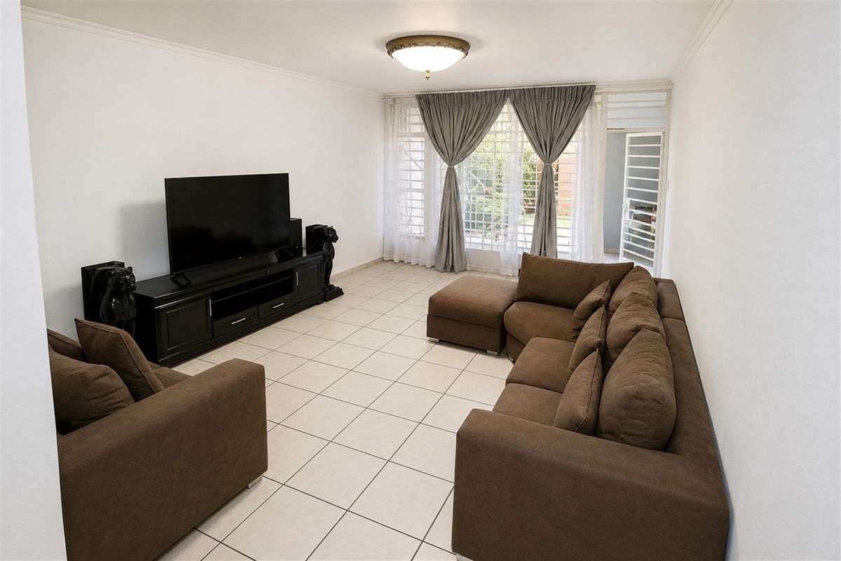 A spacious living room featuring neutral ceramic floor tiles, a flush mount ceiling light, and direct access to the outdoor area via a sliding glass door.
