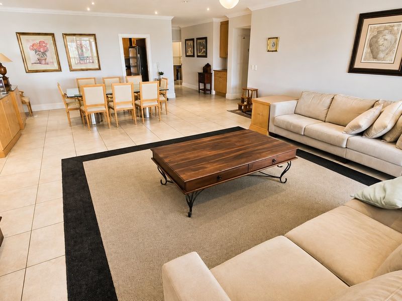 Spacious open-plan living and dining area featuring neutral tiled flooring and recessed lighting, creating a bright and versatile layout for family living.