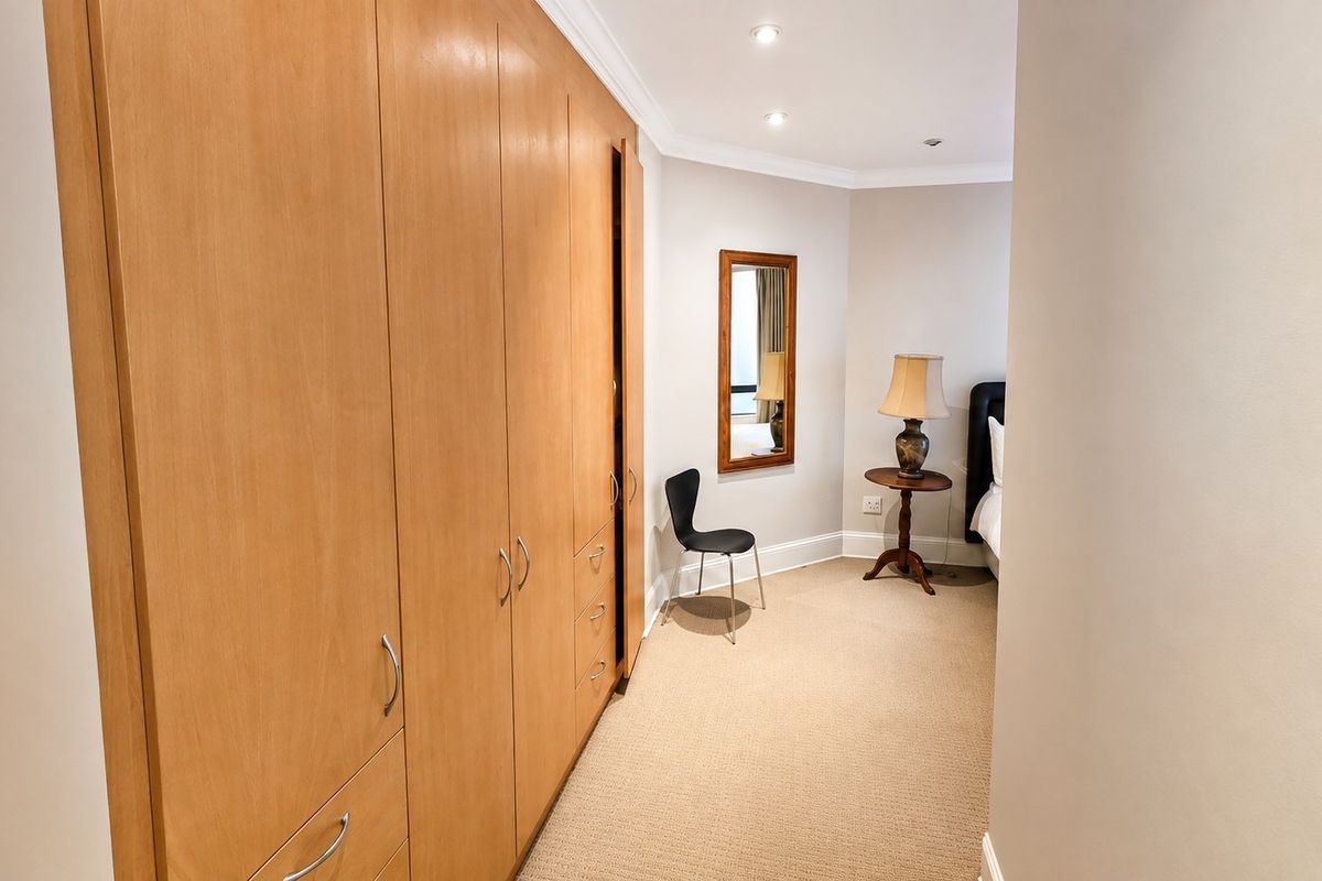 A bedroom featuring extensive built-in wooden cabinetry, recessed ceiling lighting, and neutral carpeted flooring.