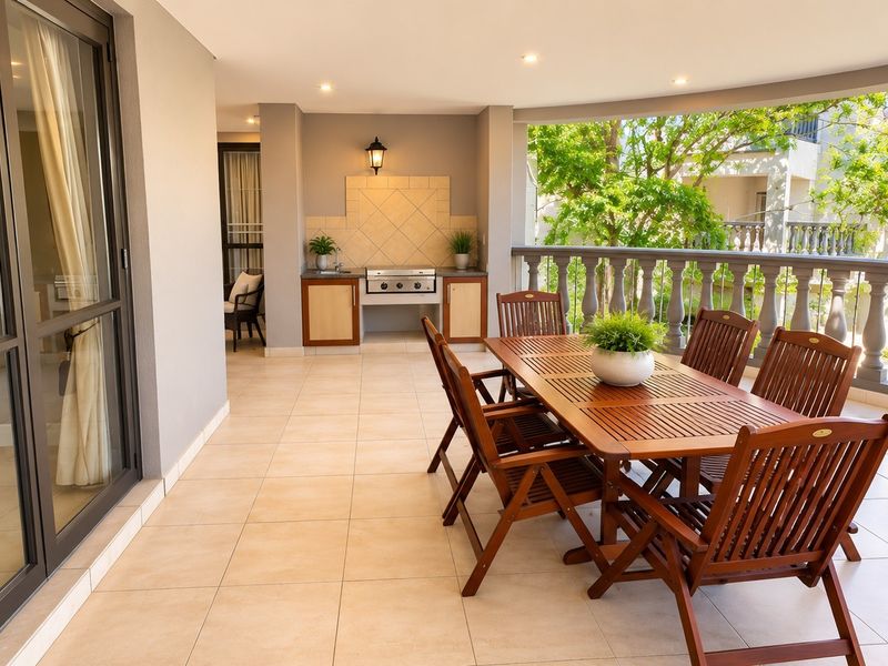 Spacious covered balcony featuring tiled flooring, a built-in braai area, and a classic balustrade, perfect for outdoor dining and entertaining.