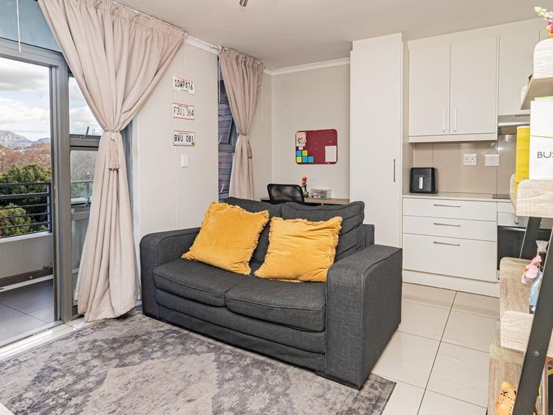 Open-plan living area featuring a compact kitchen with built-in cabinetry and direct access to a private balcony with scenic views.