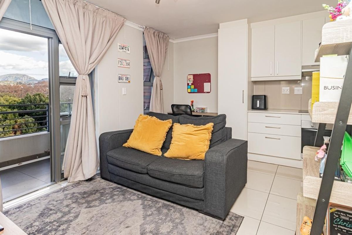 Open-plan living area featuring a compact kitchen with built-in cabinetry and direct access to a private balcony with scenic views.