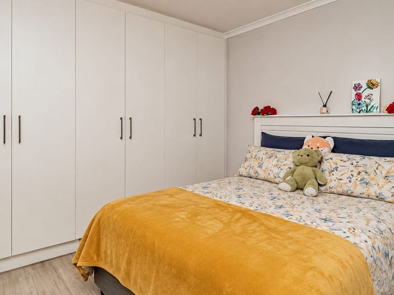 A well-maintained bedroom featuring extensive floor-to-ceiling built-in cupboards and light-toned laminate flooring.
