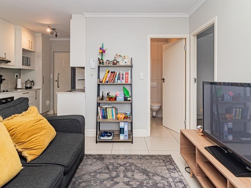 Open-plan living area featuring a modern kitchen with built-in appliances and tiled flooring, seamlessly connecting to the main living space.