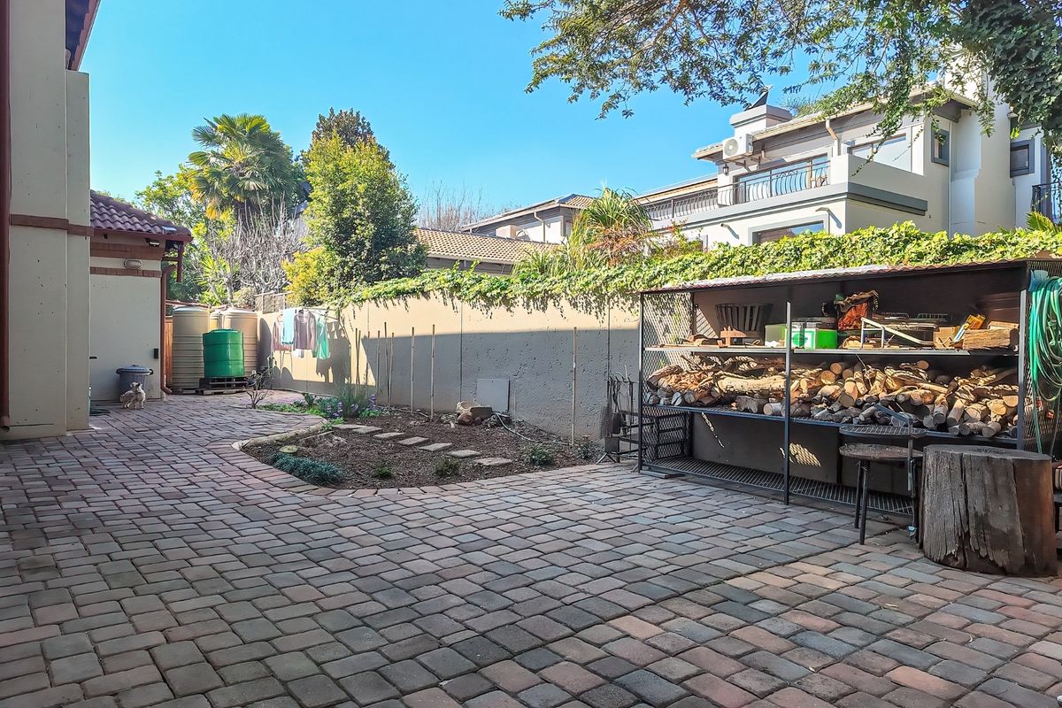 A paved rear courtyard area featuring a boundary wall, water storage tanks, and a metal storage structure.