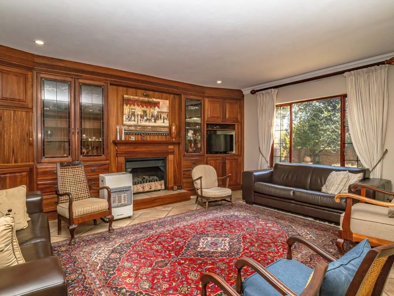 Spacious living room featuring extensive built-in wooden cabinetry, a central fireplace, and large windows providing natural light.