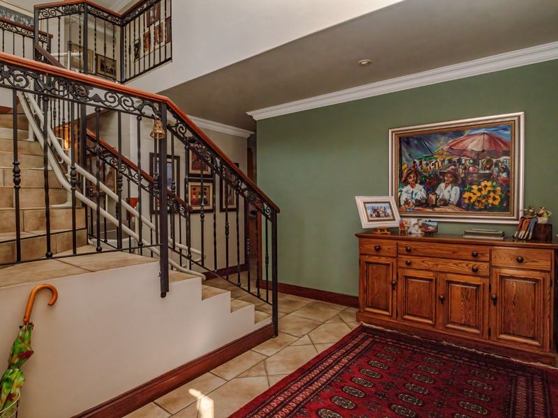 Welcoming entrance hall featuring a tiled staircase with decorative wrought iron railings and classic crown molding details.