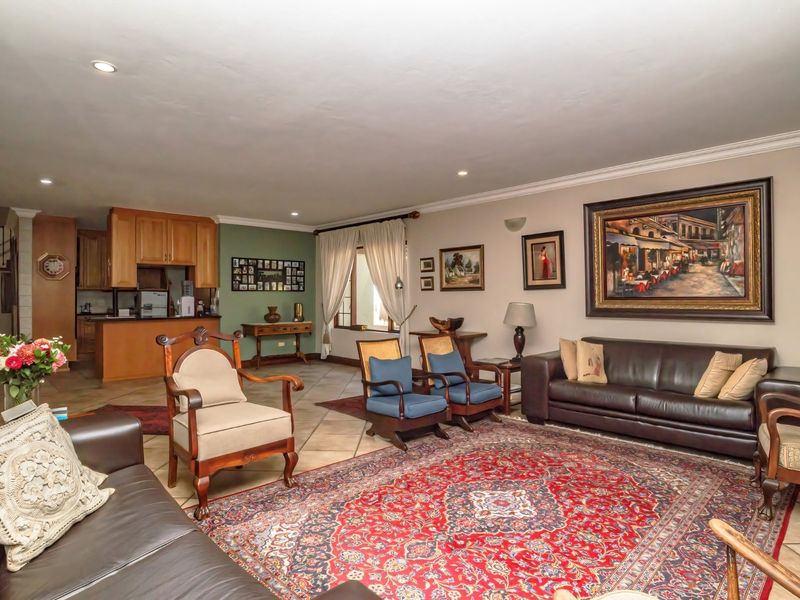 Spacious open-plan living area featuring tiled flooring, recessed lighting, and an integrated kitchen with wooden cabinetry and a breakfast bar.