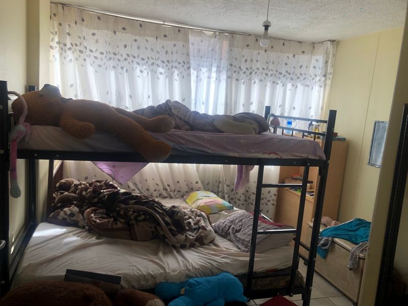A bedroom featuring tiled flooring and a textured ceiling, currently utilized with bunk bed configuration.