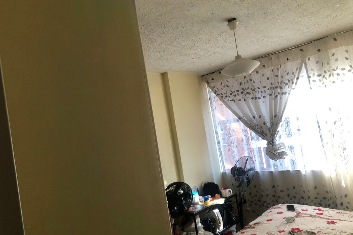 A bedroom featuring a large window and a central ceiling light fixture, requiring cosmetic updates to modernize the space.