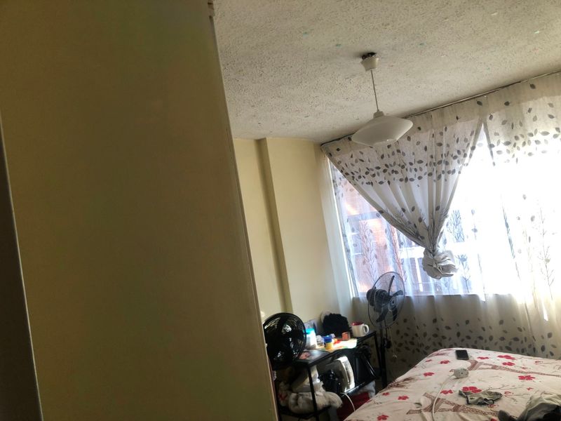 A bedroom featuring a large window and a central ceiling light fixture, requiring cosmetic updates to modernize the space.