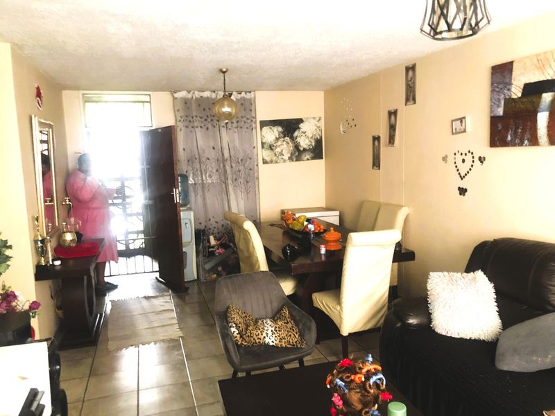 Open plan living and dining area featuring tiled flooring and direct access to the exterior through a security gate.