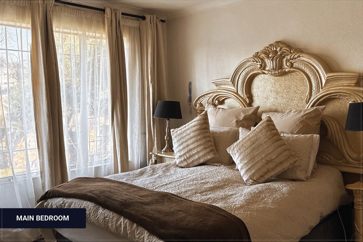 A bedroom featuring large windows with security bars, providing natural light and a neutral color palette.