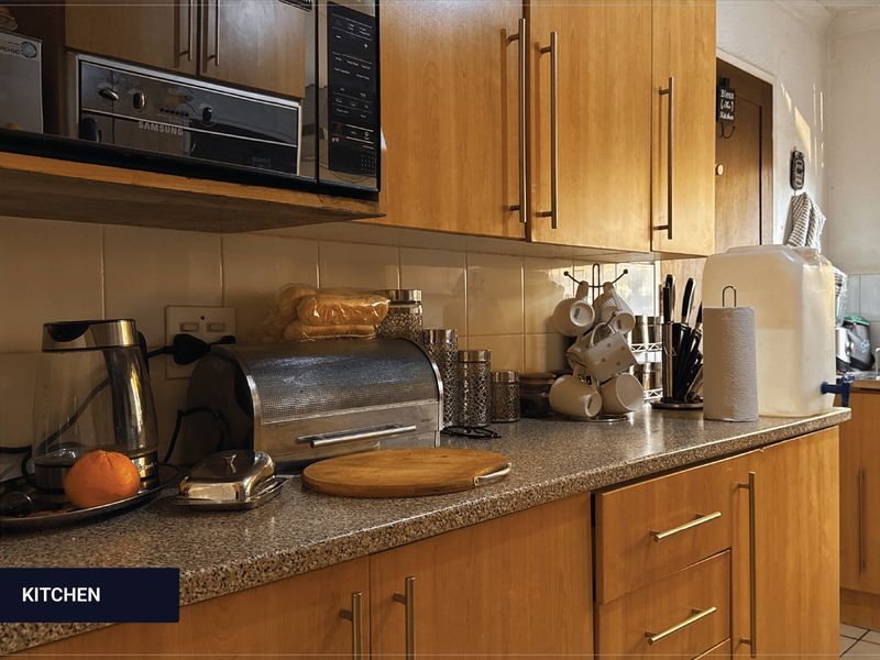 A functional kitchen featuring wooden cabinetry, a durable laminate countertop, and a tiled backsplash, providing ample storage and workspace for daily meal preparation.