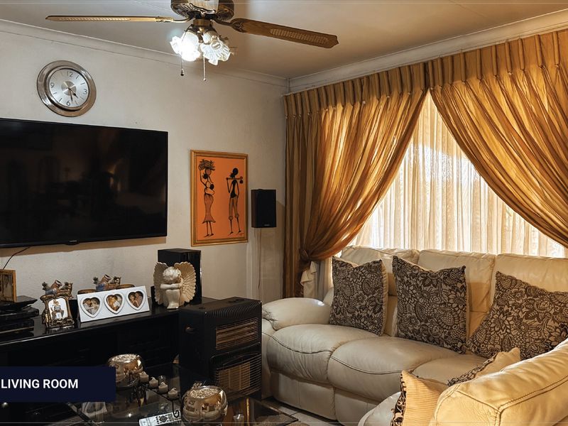 A cozy living room featuring a ceiling fan and large window with curtain tracks, providing a functional space for relaxation.