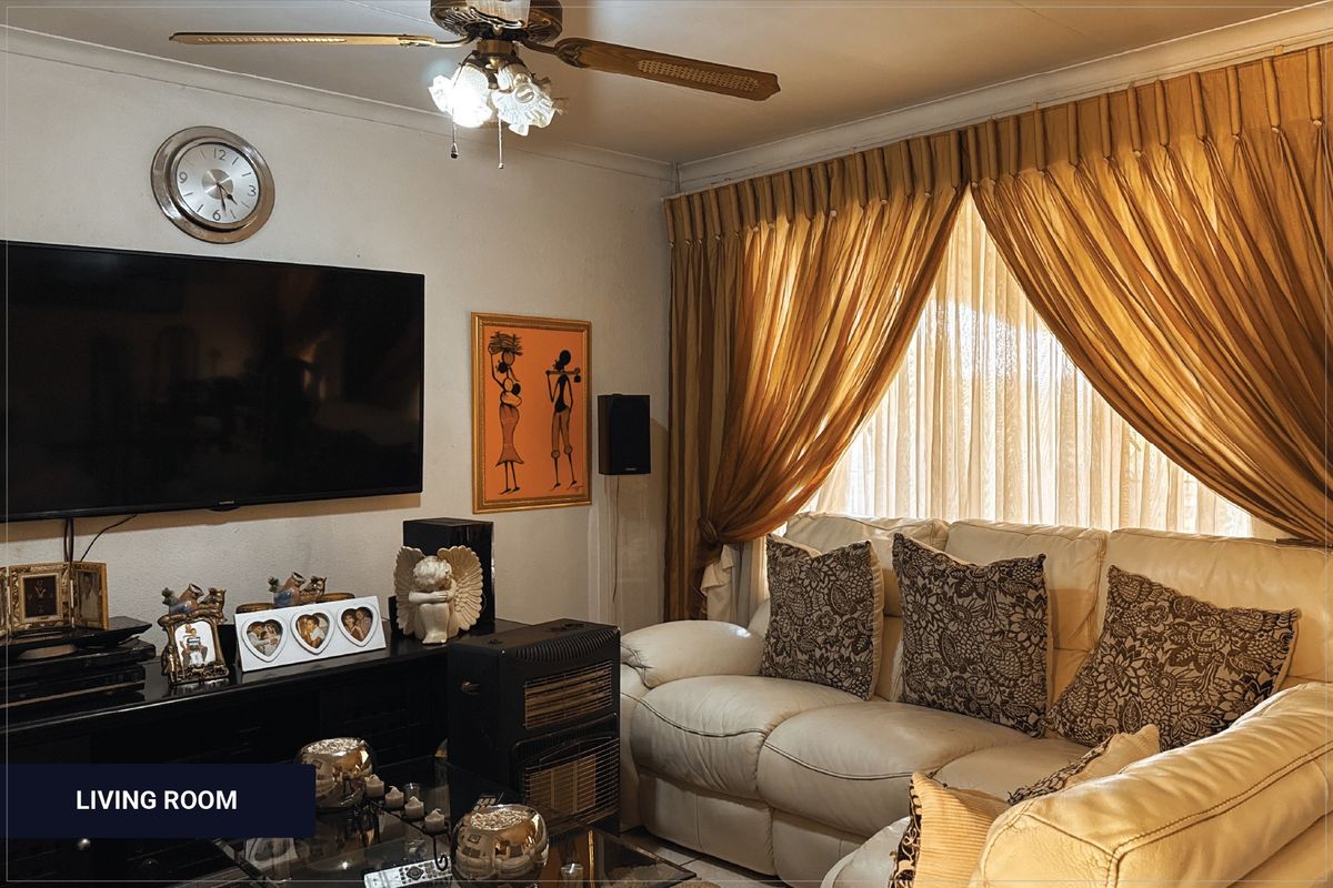 A cozy living room featuring a ceiling fan and large window with curtain tracks, providing a functional space for relaxation.