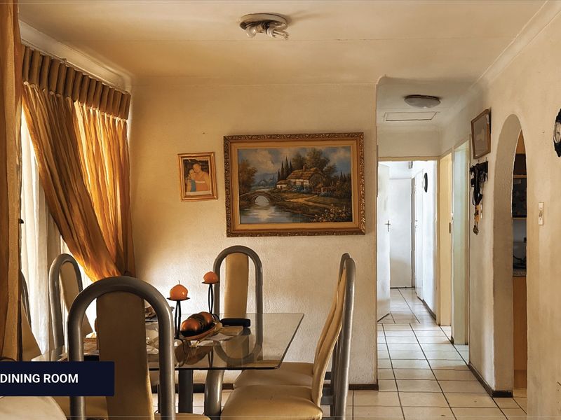 Dining area featuring tiled flooring and a classic archway leading to the hallway, offering a traditional layout with potential for modern updates.