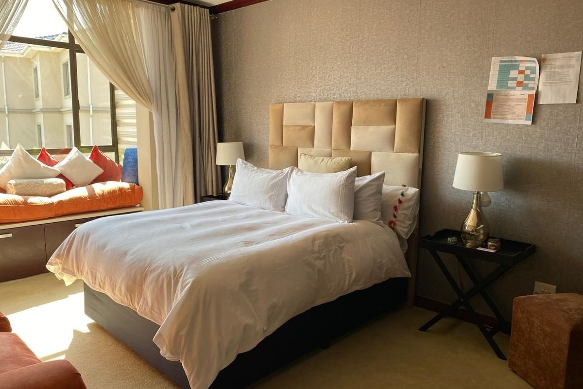 A well-lit bedroom featuring a built-in window seat, textured wall finishes, and crown molding, providing a comfortable and functional living space.