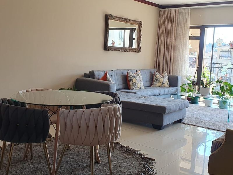 A bright open-plan living and dining area featuring polished tiled flooring and large sliding glass doors leading to a balcony.